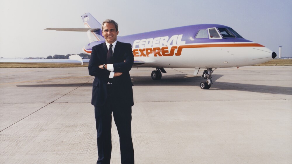 Fred Smith poses before a Federal Express airplane.