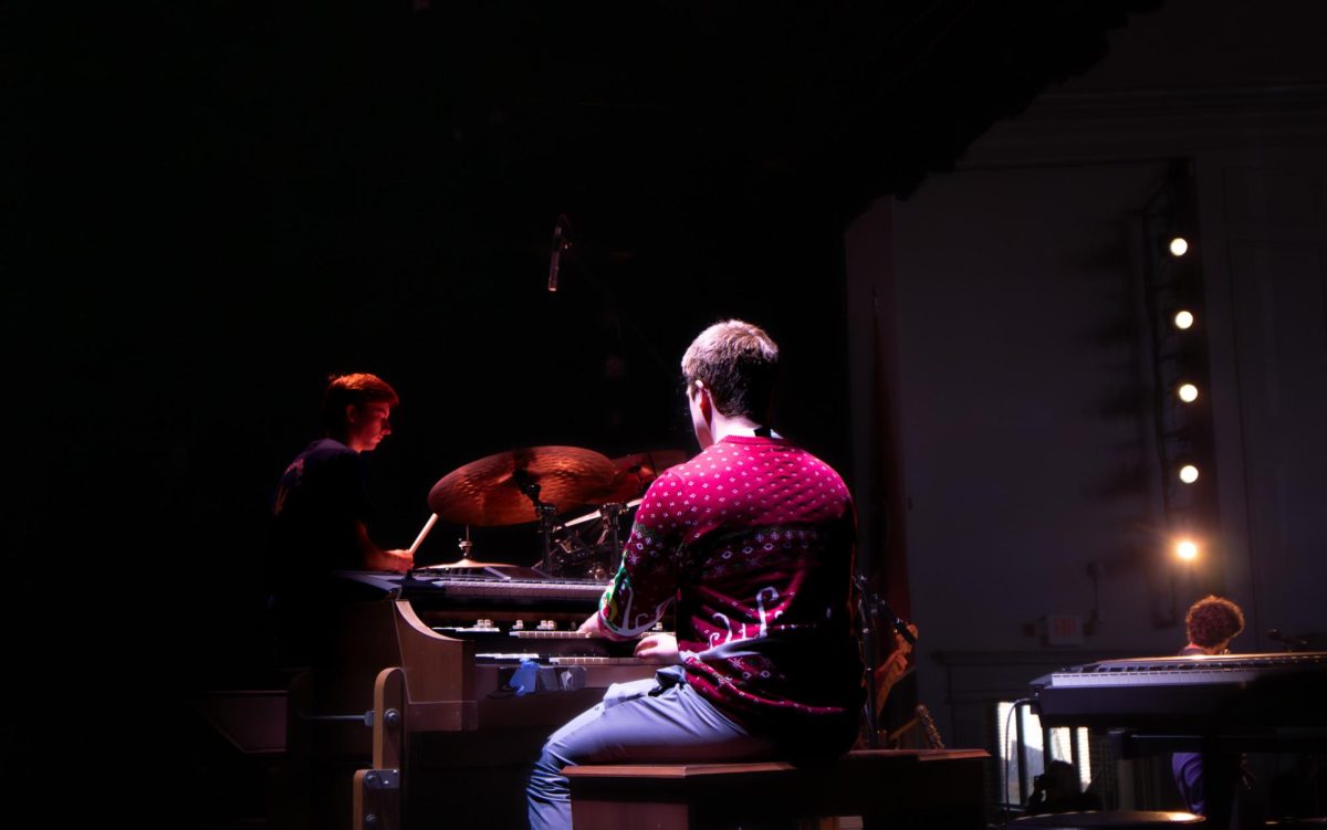 Kellett Giles (12) plays the keys, while Fletcher Taylor (12) drums through the darkness, illuminated by a stage light.