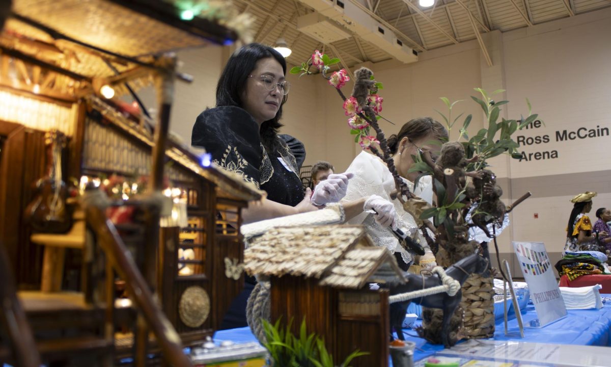 IN MINISCULE: Representatives of the Phillipines prepare food at the beginning of the International Fair, framed by a model of a traditional Filipino home. Their booth was one of 29 total at the fair, including an additional international book table, student artwork booth and an International Exchange Student Programs booth.