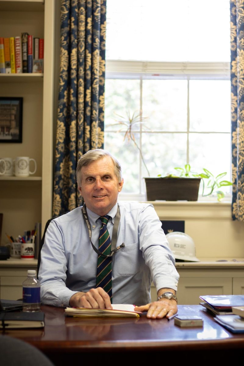 Headmaster Pete Sanders sits at his desk in his office, smiling.